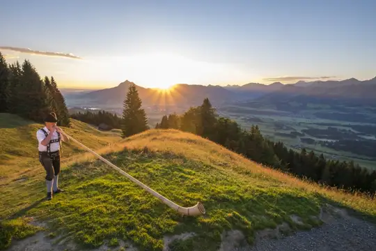 Sonnenaufgang auf dem Ofterschwanger Horn begleitet von einem Alphorn
