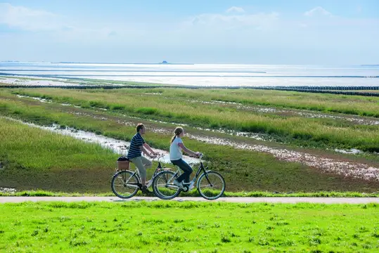 Pärchen mit Fahrrädern auf dem Deich des Wattemeeres bei Ockholm